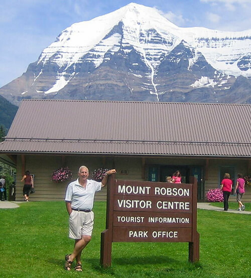 MBA grad John Lyotier beside a sign with Mount Robson in the background