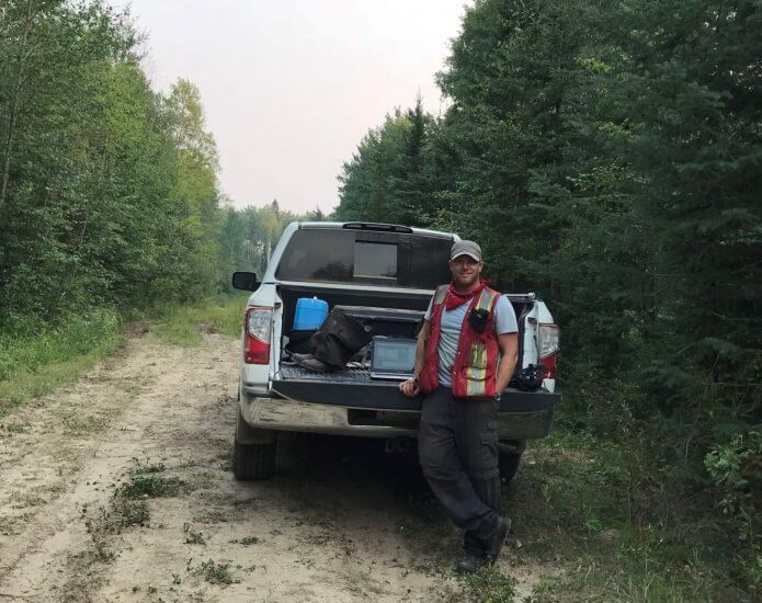 scott ketcheson standing in front of a truck doing field research