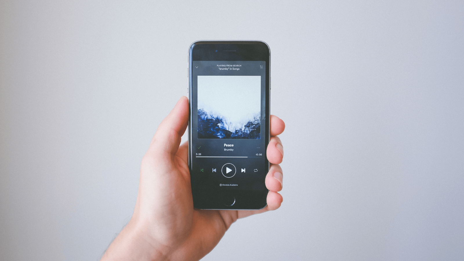 man holding iphone with spotify displayed on screen