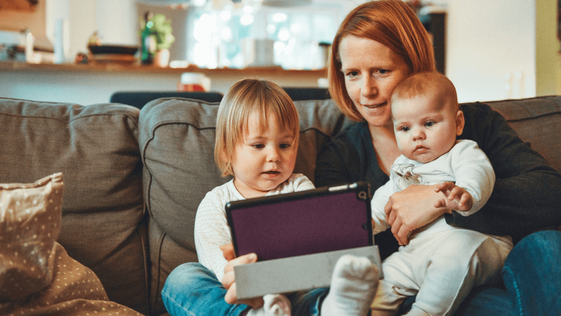 mom with two young children on her lap looking at a tablet