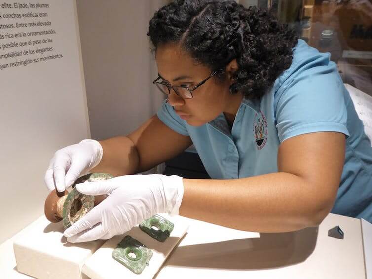 woman installing ancient belongings at a museum
