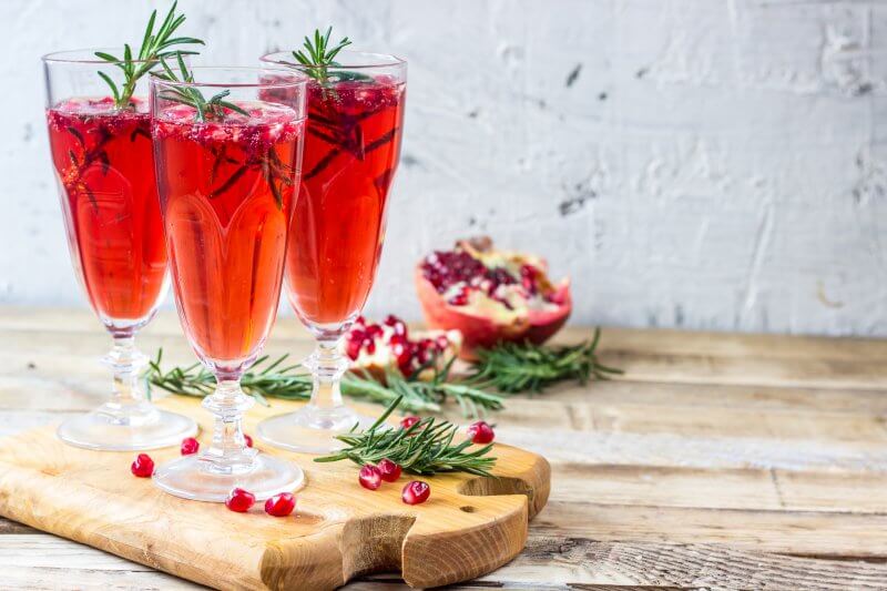 Pomegranate mocktail with rosemary in glasses on wooden background