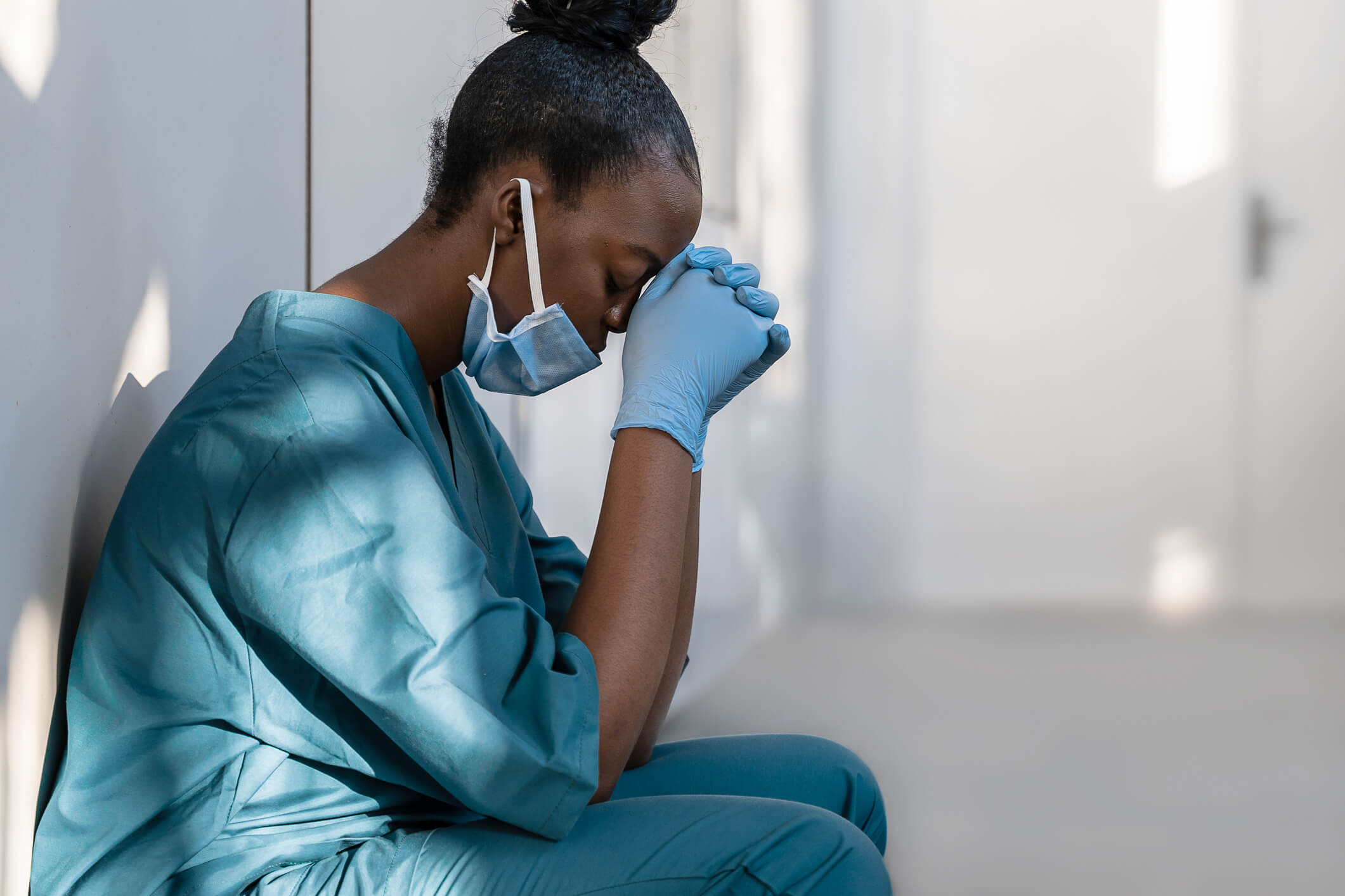 Tired Black nurse sitting with hands against her face