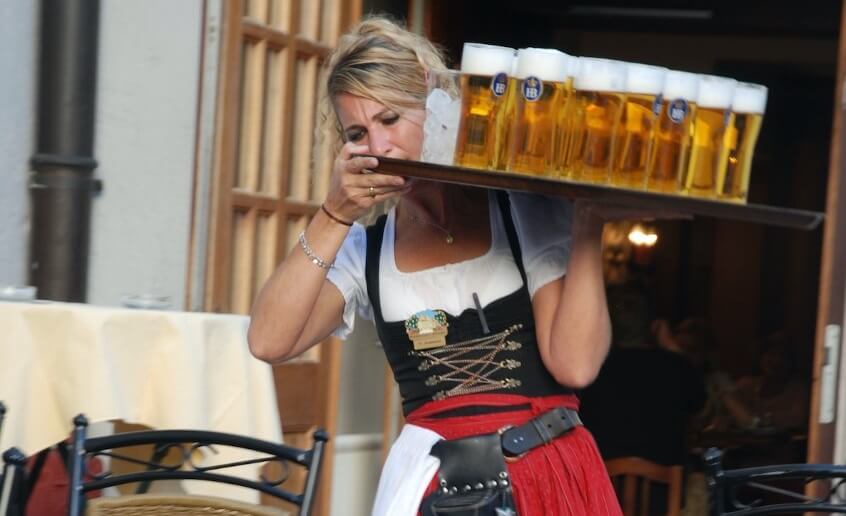 A woman carrying a serving tray full of pints of beer