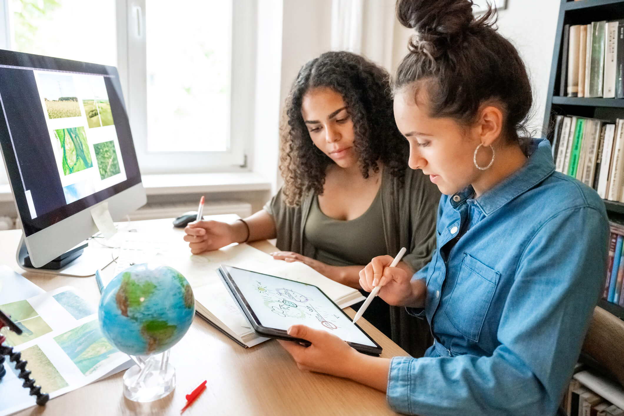two young woman preparing together concepts for climate protection on desk indoors
