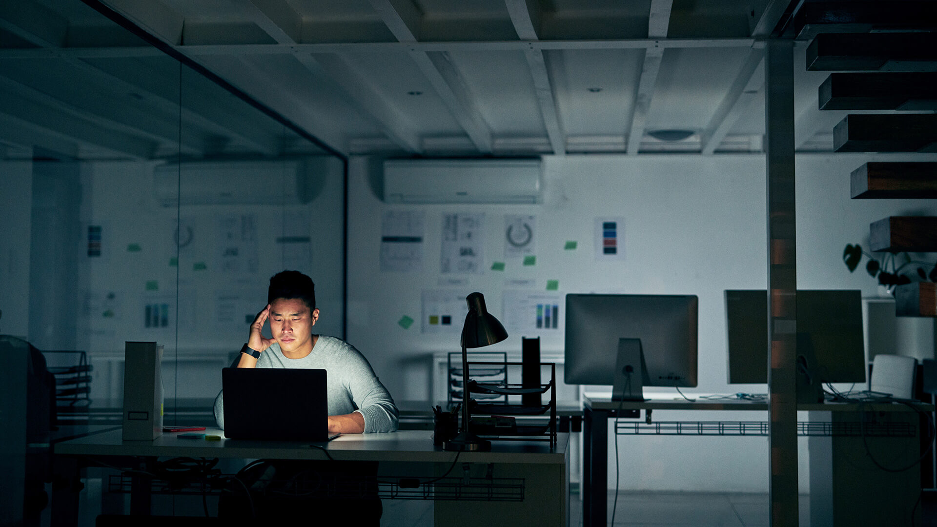man working alone on a computer in a dimly lit room