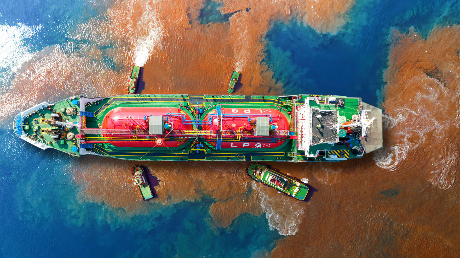 An aerial view of an oil tanker that is spewing oil into the ocean as cleanup crews respond.