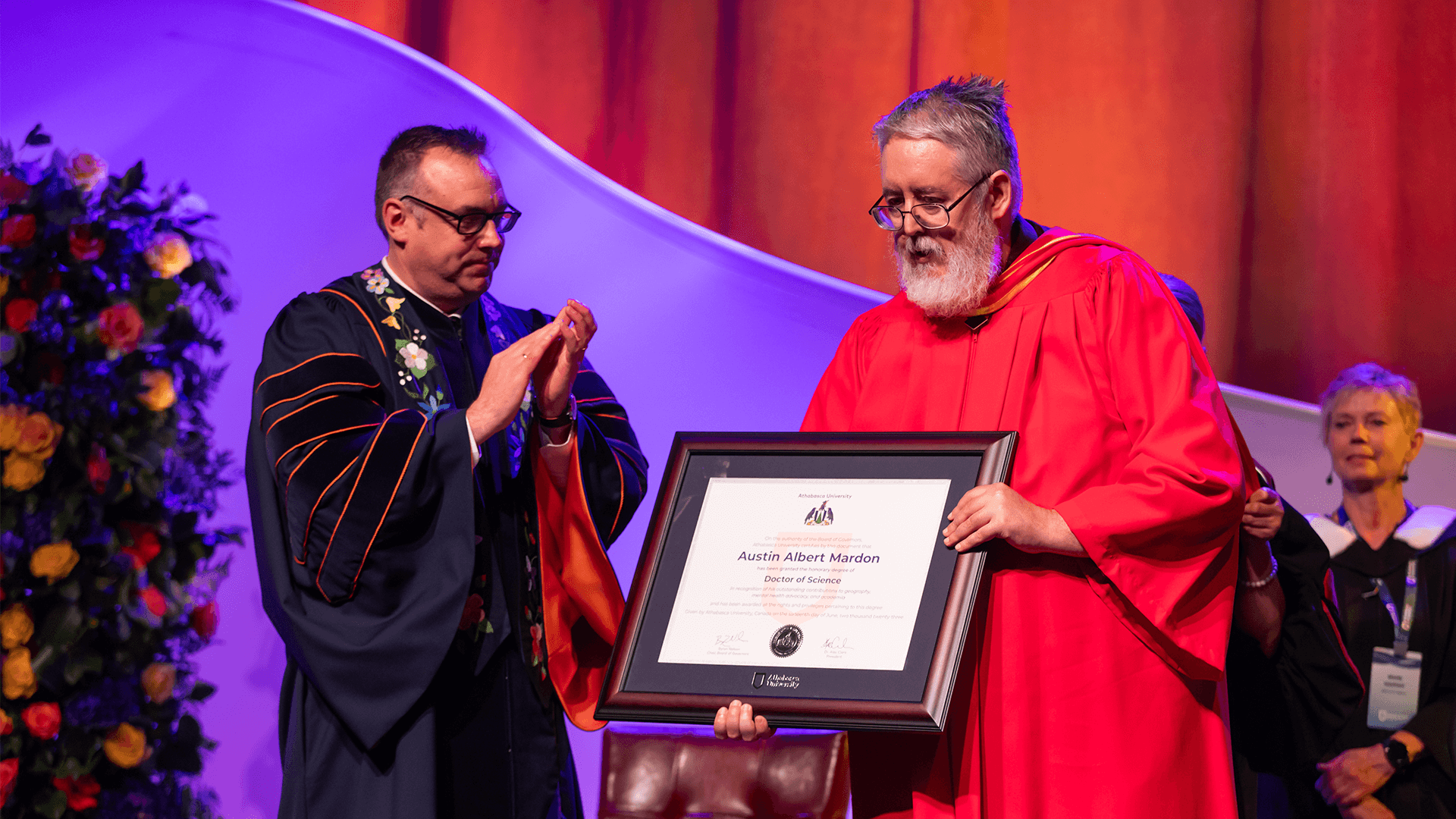 photo of AU president Dr. Alex Clark who is clapping next to 2023 Honorary Doctor of Science Austin Mardon