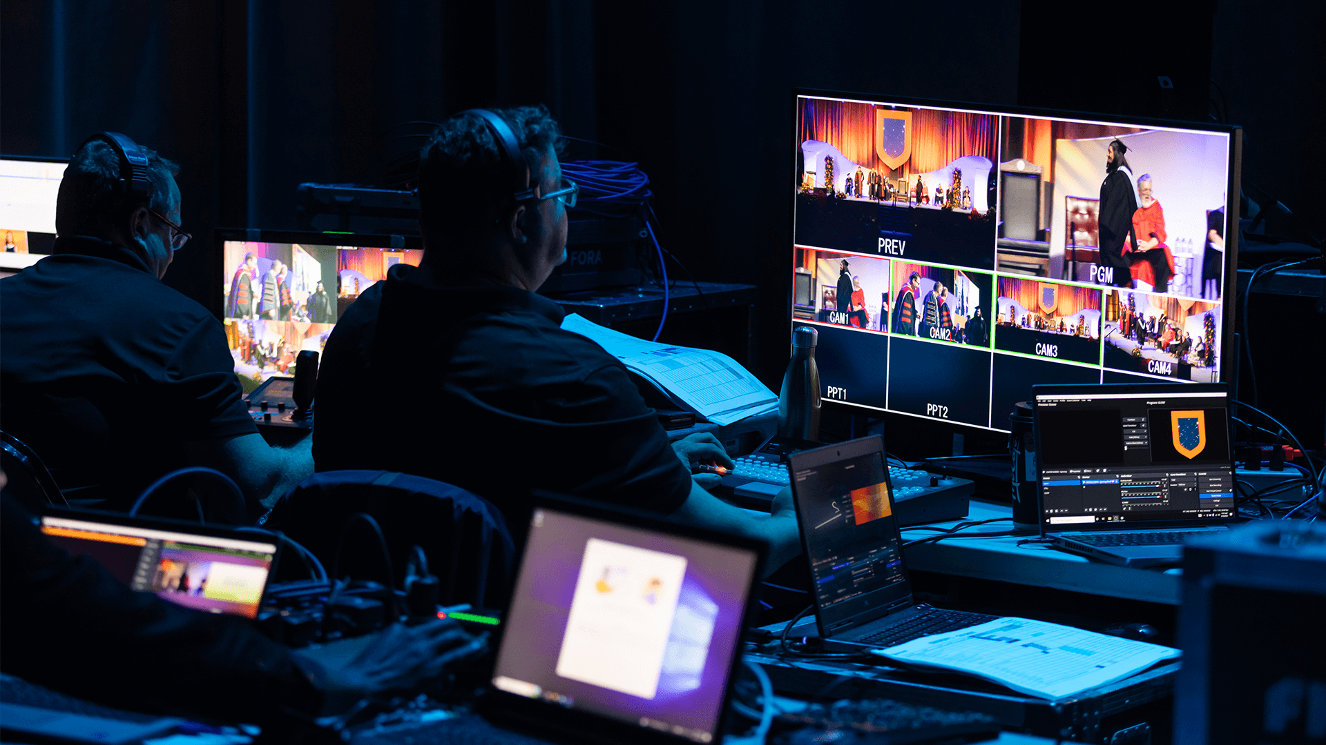 clost up backstage shot of a technician sitting at a station with a television monitor showing multiple camera angles